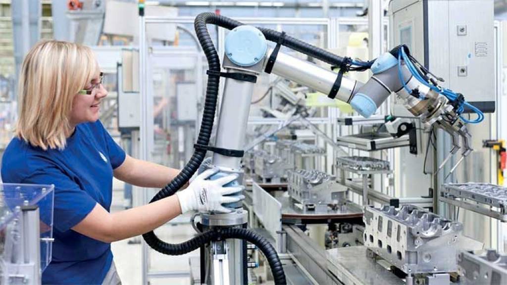 Workers in safety gear operating industrial robots on manufacturing floor at RTP's maintenance center